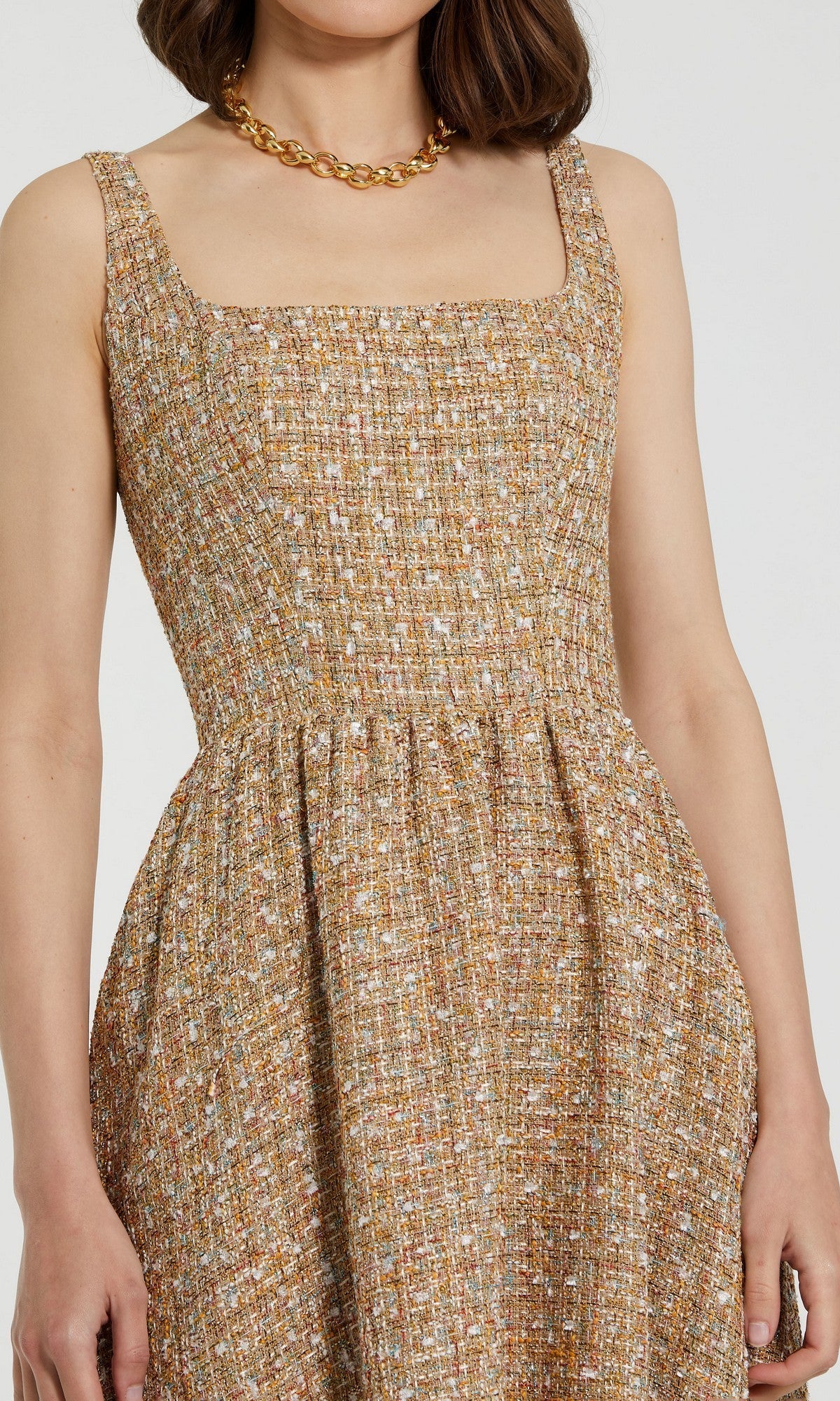 A woman wears the Mac Duggal 21071 Boucle A-Line Midi Dress, a sleeveless tan and white textured midi with a square neckline, paired with a gold chain necklace.